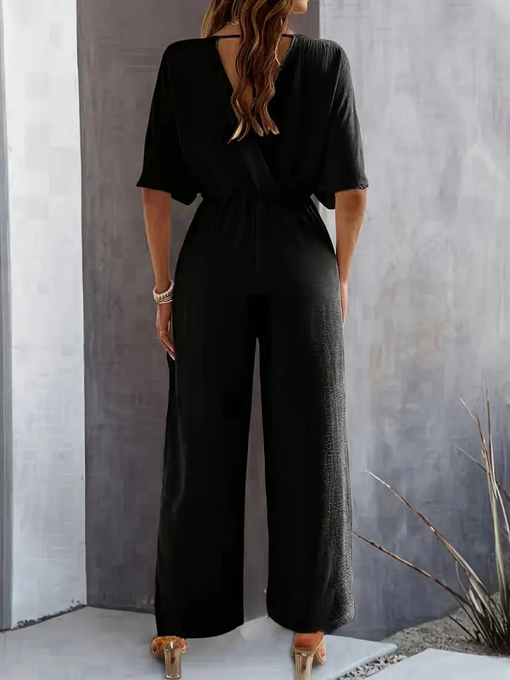 Elegant dam jumpsuit i draperad design med djup v-ringning för fest och vardag