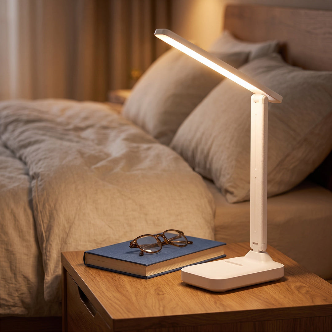 Stilren bordslampa för läsning tänd på ett skrivbord i ett dämpat rum.