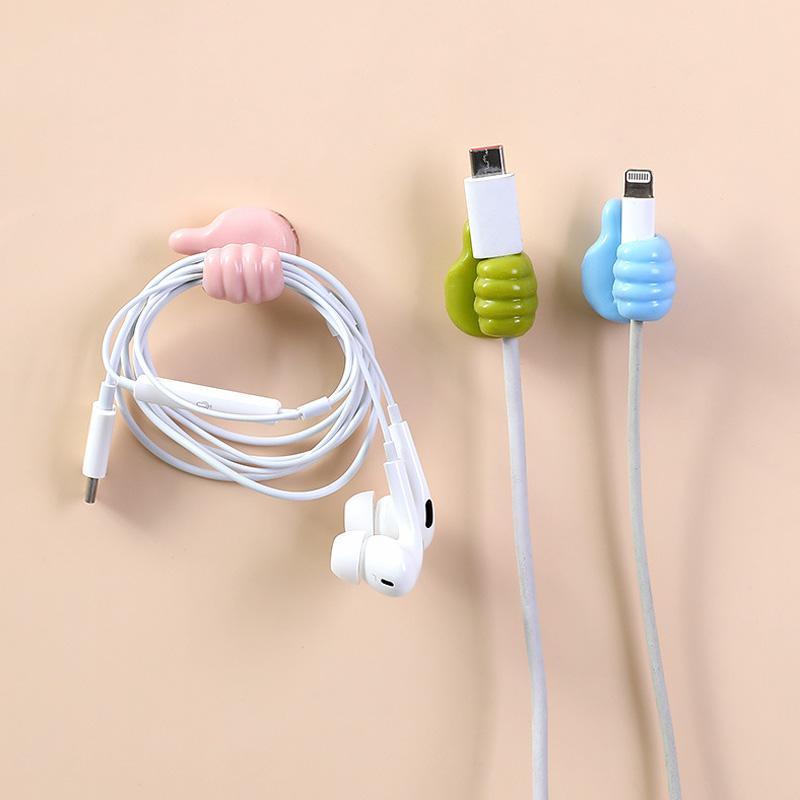 Grön självhäftande tumme upp kabelhållare på slät yta, effektivt organiserar kablar, passar dator- och USB-kablar.