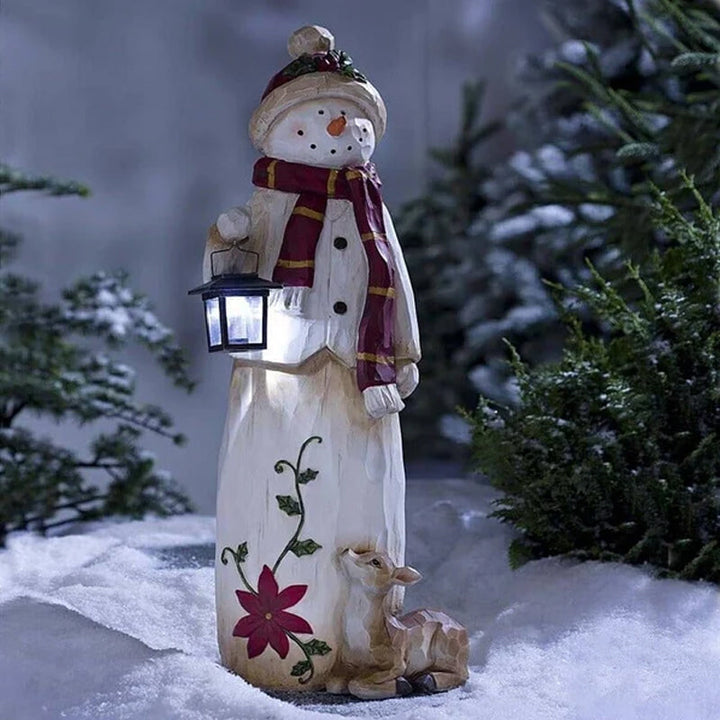 "Handgjord snögubbe juldekoration med LED-lykta, snöhatt, röd halsduk i trädgård, för magisk julstämning i hemmet."