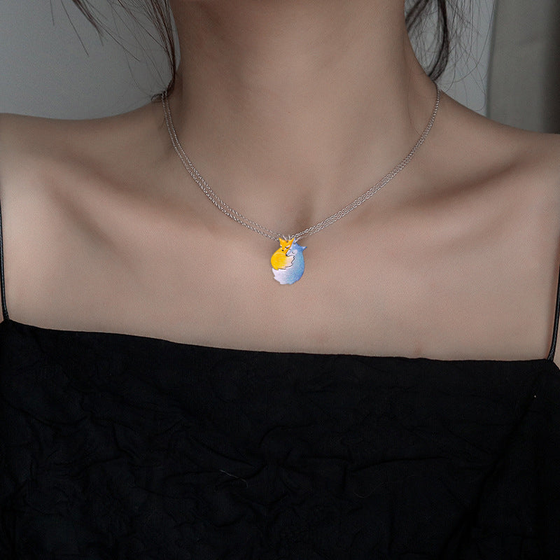 Handmålat parhalsband i stål med motiv av kramande räv och varg, perfekt för par och vänner.