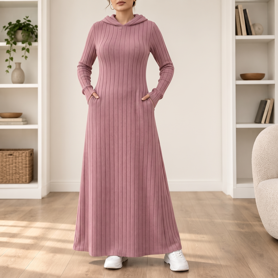 Kvinna i rosafärgad ribbad lång klänning med huva och fickor