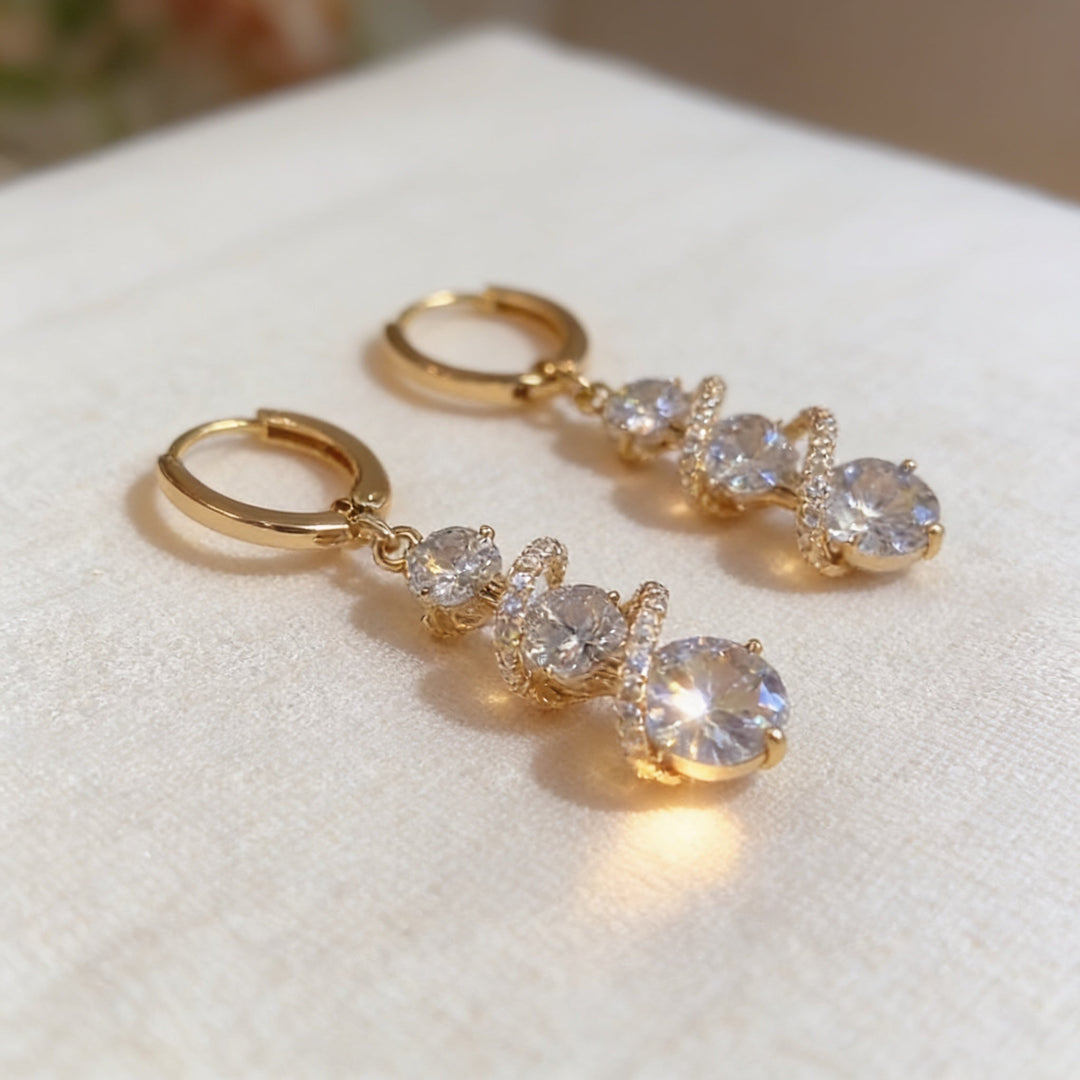 Närbild på Lucienne spiralörhängen i guld och kristall