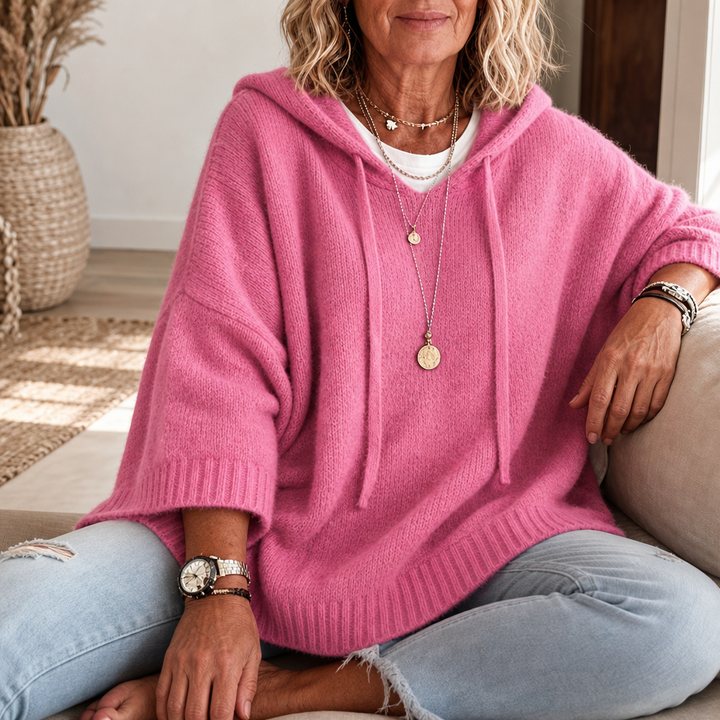 Närbild på kvinna som sitter i rosa oversized huvtröja