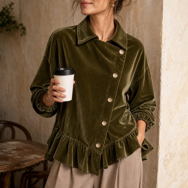 Kvinna i olivgrön blus med asymmetrisk krage som håller i en kaffemugg