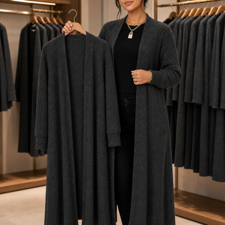Kvinna i butik som håller upp en mörkgrå lång ribbad kofta bredvid sig