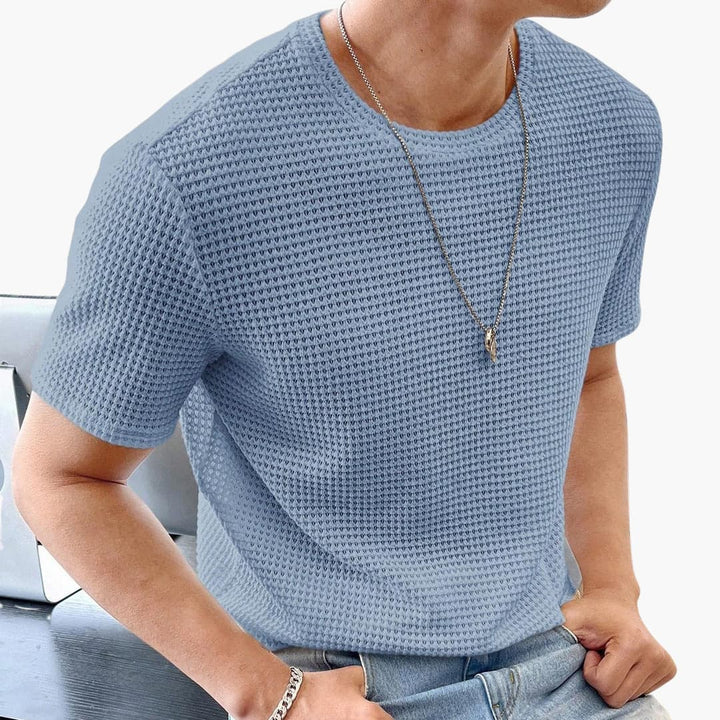 Detaljerad vy av en herr T-shirt med rund hals och bekväm våffelstruktur. Perfekt för alla tillfällen.
