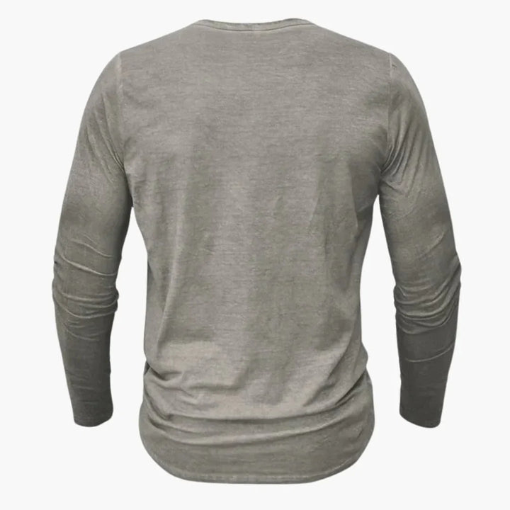 Man bär en modern, långärmad Henleytröja med knappslå, perfekt passform för stilren vardagslook. Herrkläder.