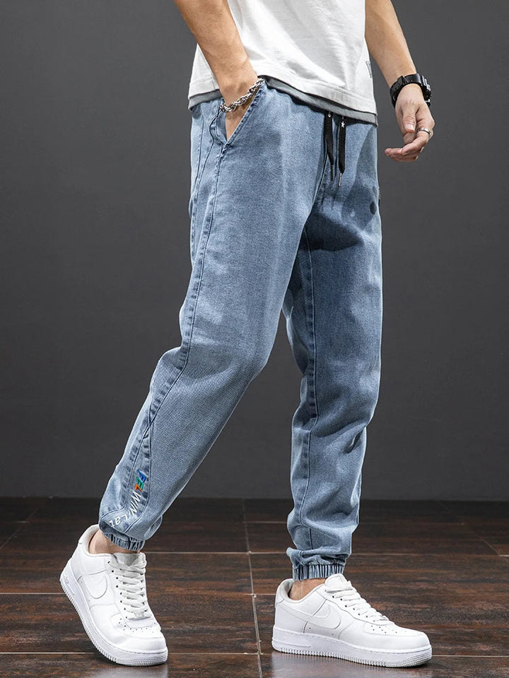 Närbild på ljusblå jeans med dragskor i midjan och vita skor