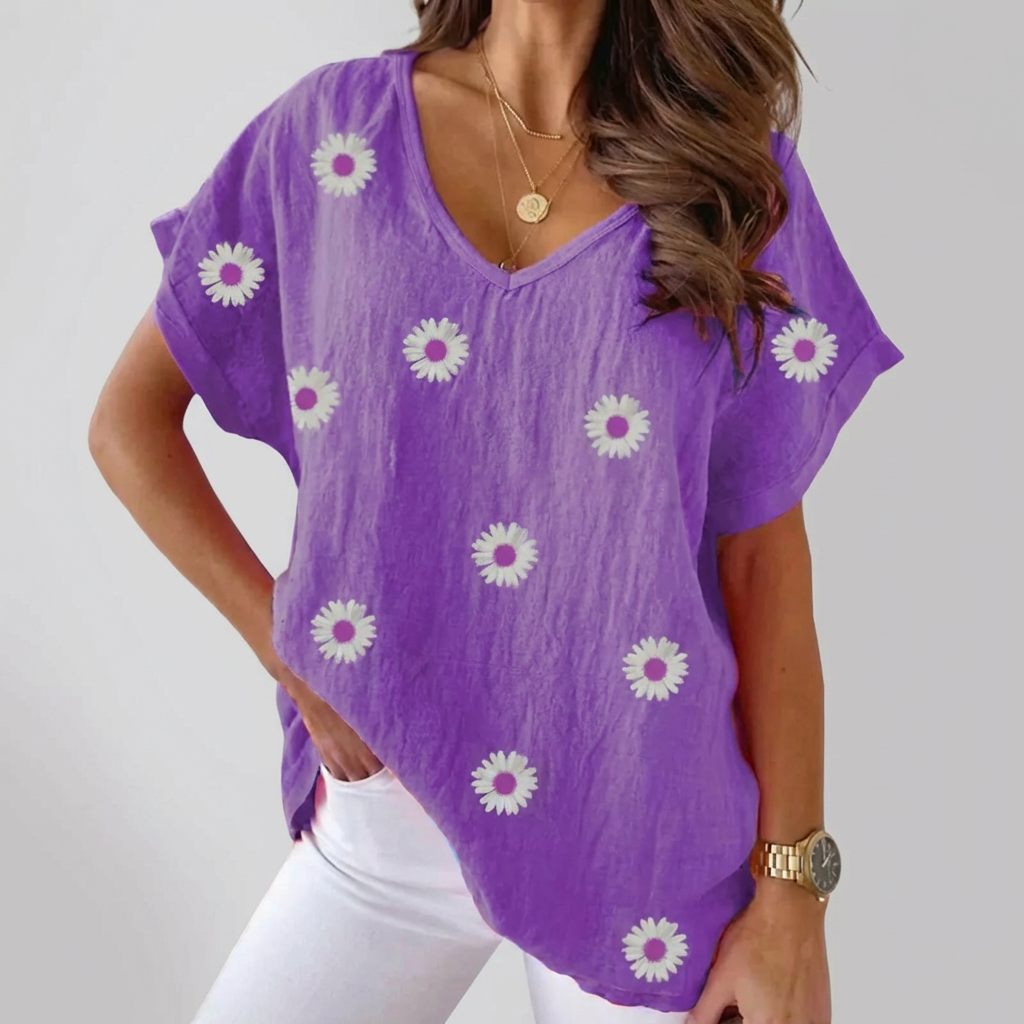 Kvinna i lila blus med blomstertryck mot ljus bakgrund