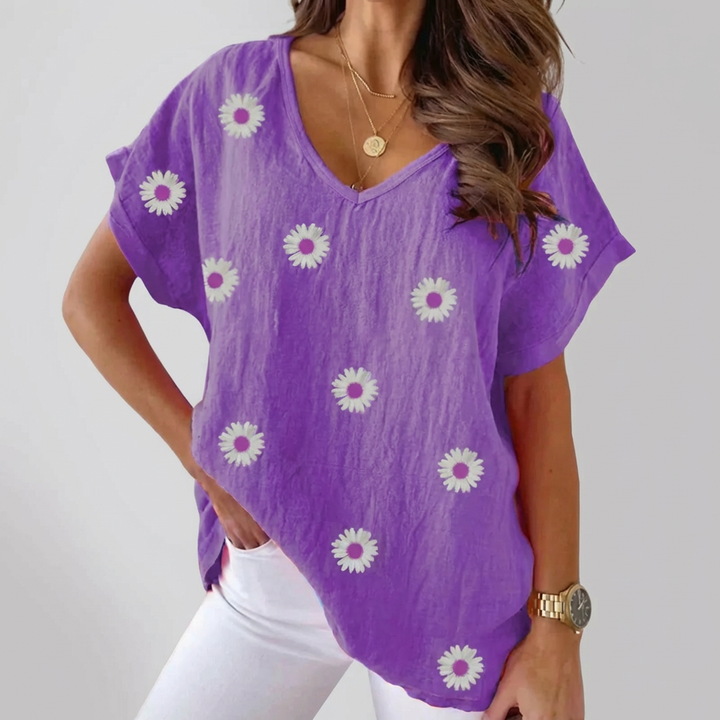 Kvinna i lila blus med blomstertryck mot ljus bakgrund