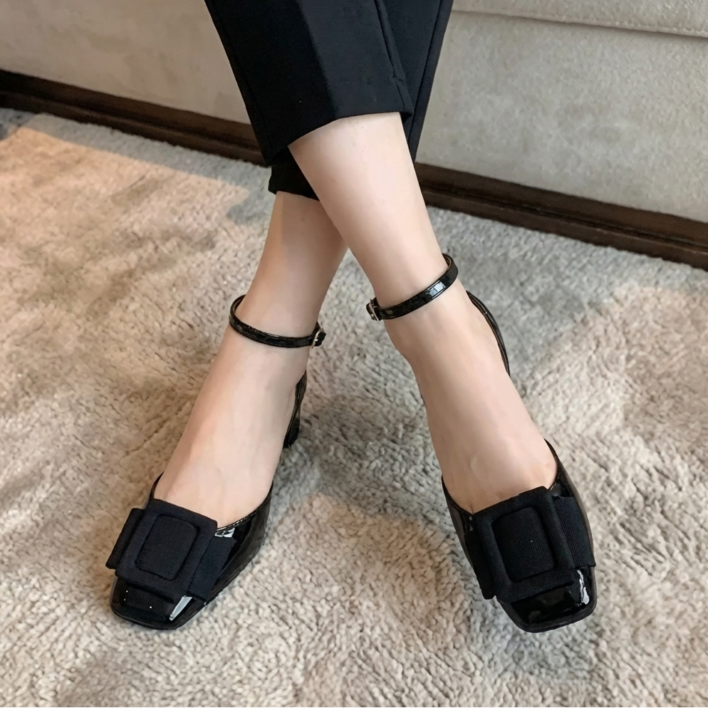 Damkläder med svarta lackpumps och blockklack på matta
