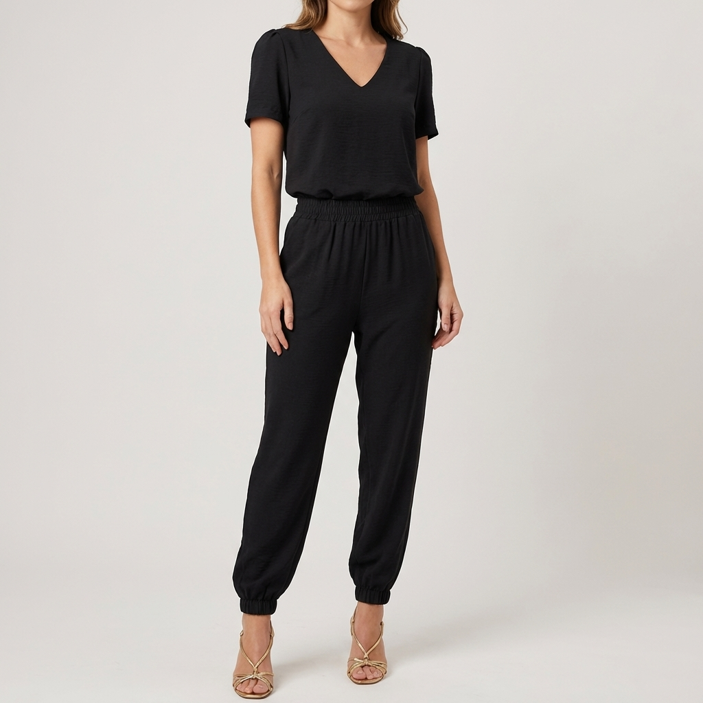 Kvinna i svart kortärmad jumpsuit med V-ringning framifrån