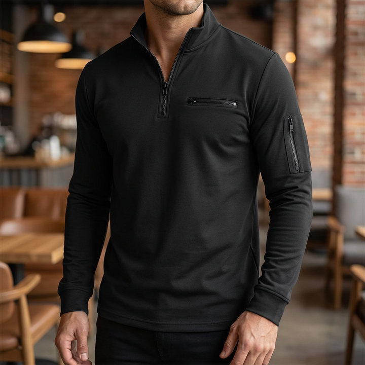 Framifrån av en man i svart zip-up tröja med bröstficka i en restaurangmiljö