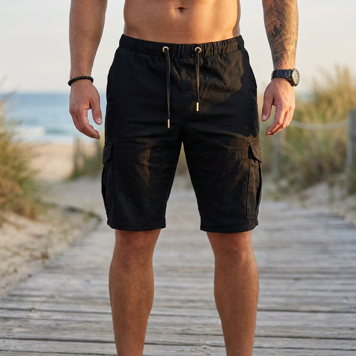Man i svarta cargo shorts framifrån på strandpromenad