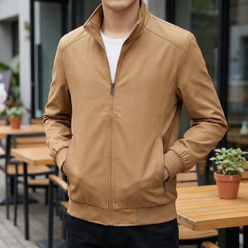 Man bär en stilren khaki-färgad vindresistent sommarjacka vid ett utecafé
