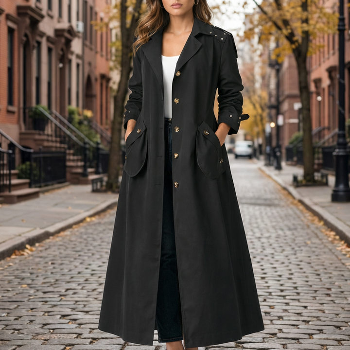 Kvinna som bkommer i en svart trenchcoat med huva på gata
