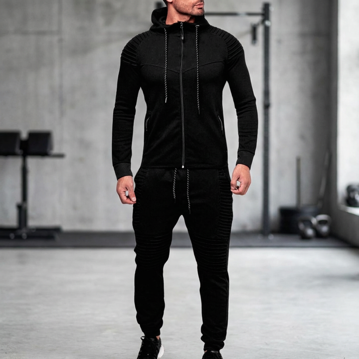 Man iklädd svart hooded tracksuit i en industriell träningslokal