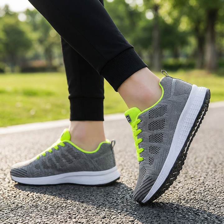 Grå och limegröna idrottssneakers för kvinnor sedda från sidan utomhus