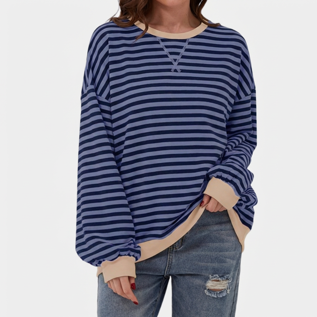 Studiobild på dam i mörkblå oversized randig tröja och jeans