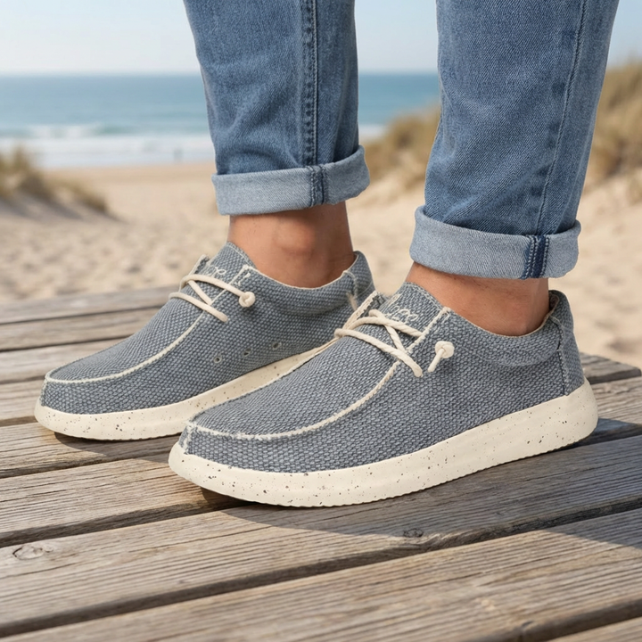 Grå lågskurna snörskor för män på trätrall nära strand