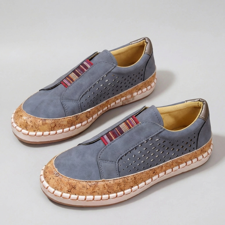 Två blå slip-on lågtoppssneakers i avslappnad stil uppställda på grå bakgrund