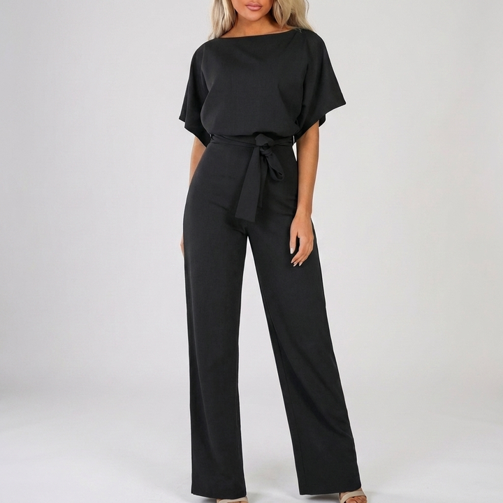 Svart damjumpsuit med kort ärm och knytbälte mot neutral bakgrund