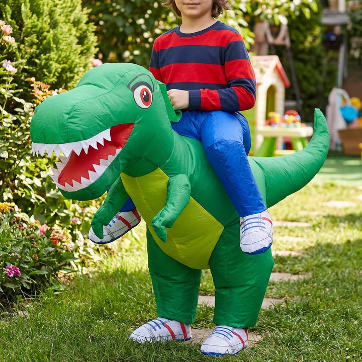 Barn som rider på en grön dinosauriekostym utomhus i trädgården