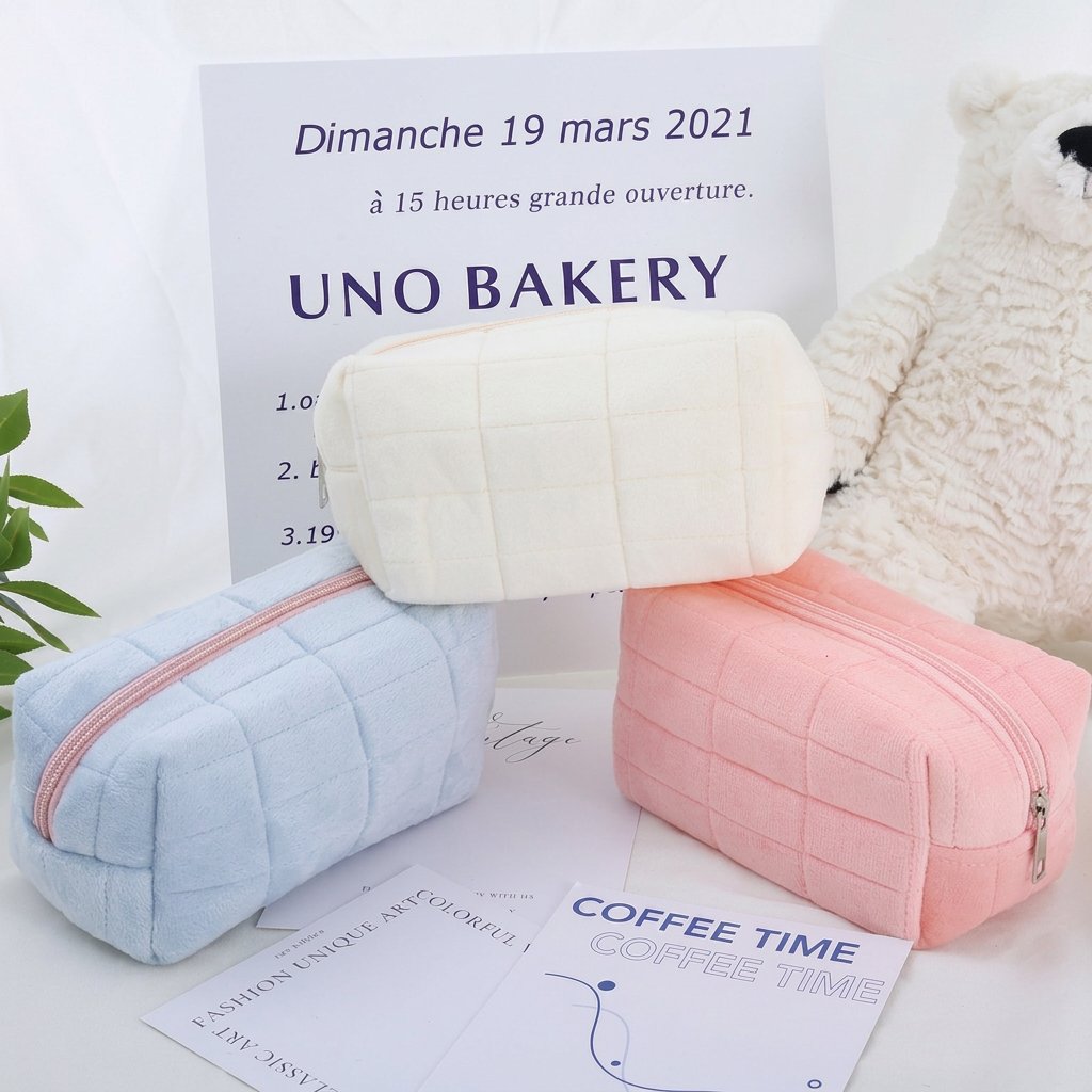 Tre pastellfärgade kosmetikaväskor i blått, vitt och rosa uppställda tillsammans