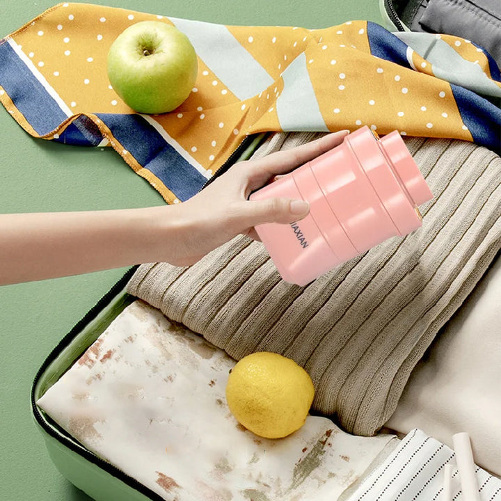 "Hopfällbar mini-juicepresskopp i rosa, kompakt design med rostfritt stålblad, idealisk för hälsosamma drycker på språng."