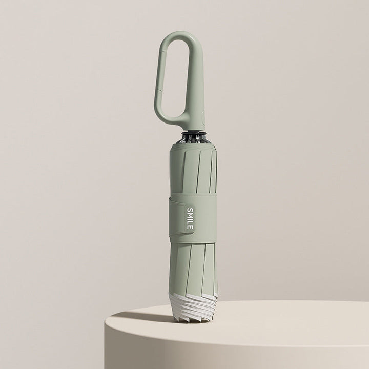 Grönt vindtåligt reseparaply med smidig design och upphängningsögla