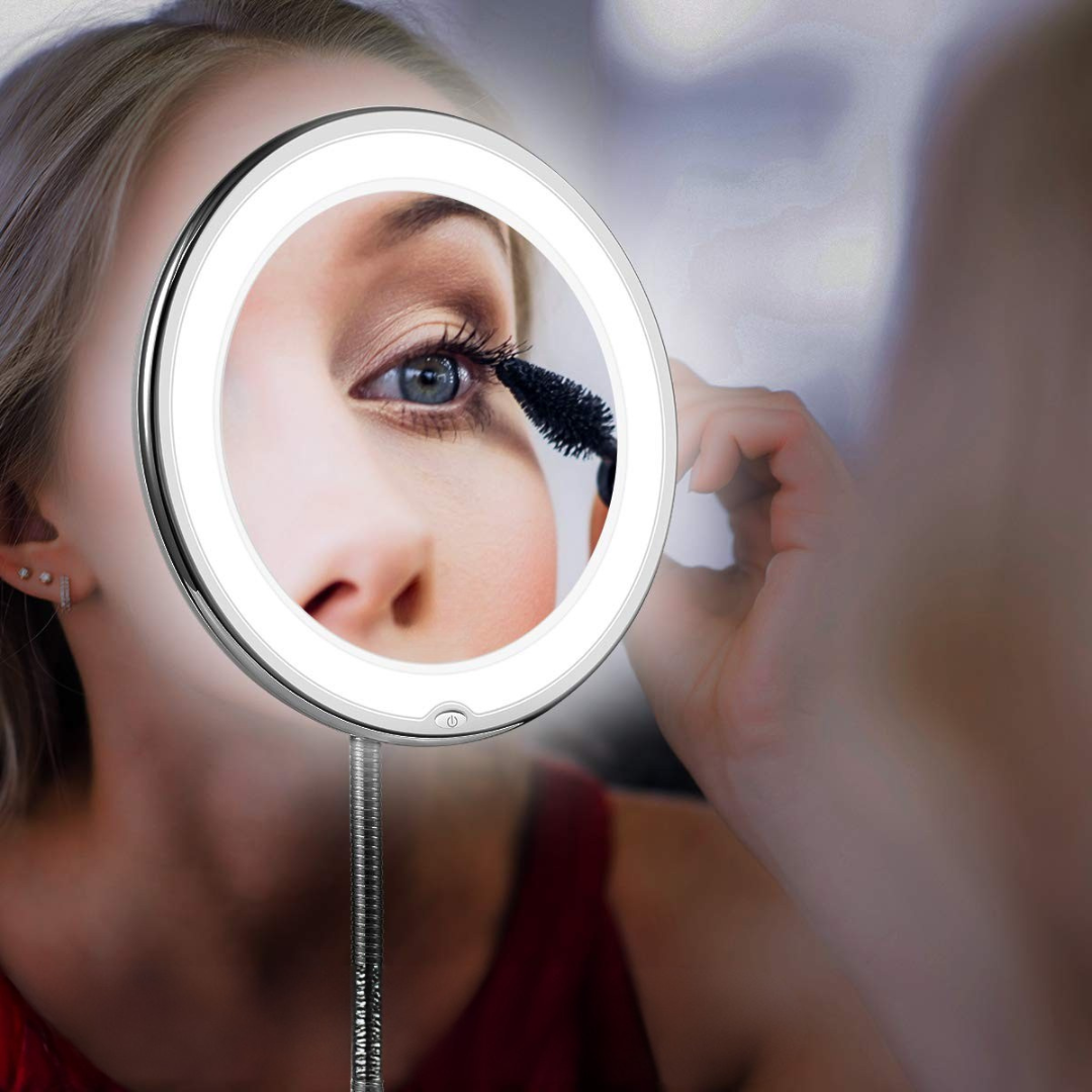 Kvinna som applicerar makeup framför upplyst förstoringsspegel
