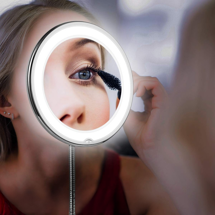 Kvinna som applicerar makeup framför upplyst förstoringsspegel