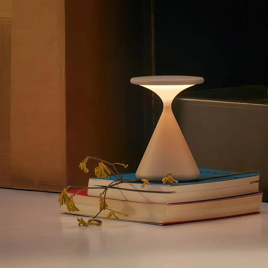 Ljus LuminaHour trådlampa med timglas placerad på böcker i dämpad belysning