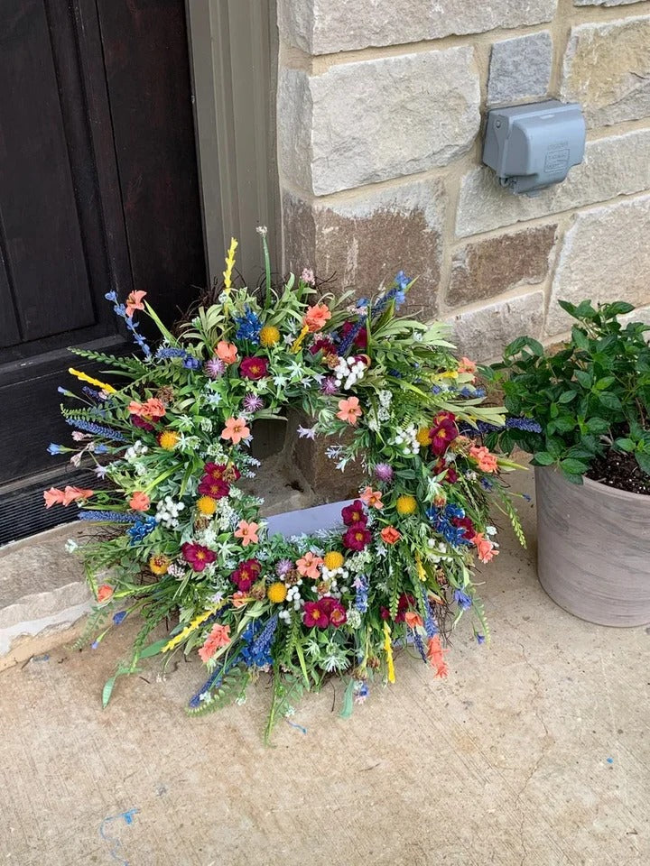 Vildblomsterkrans placerad på marken vid en stentrappa