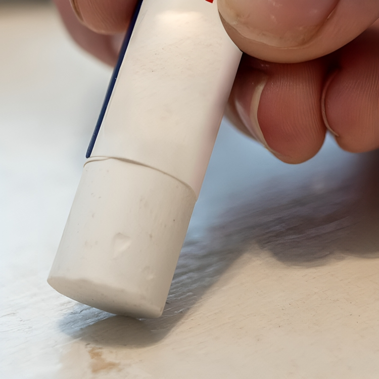 Närbild på en vit träreparationspenna som appliceras på en träyta