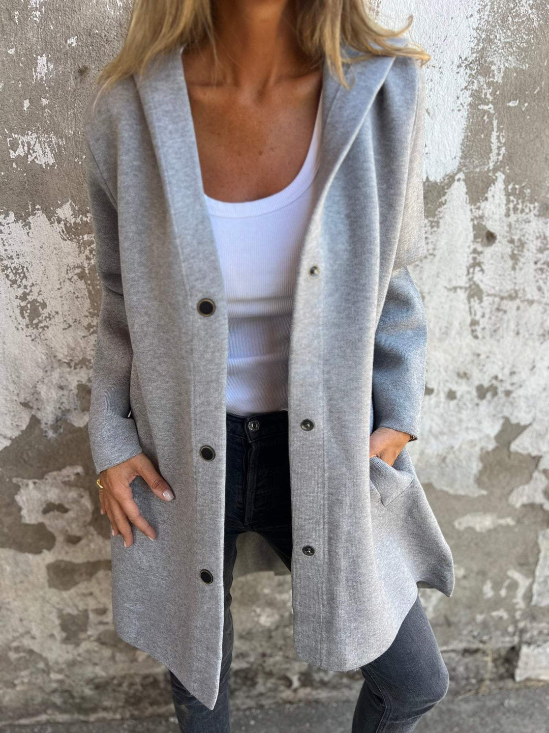 Närbild på en lång grå cardigan med fickor och knäppning framtill