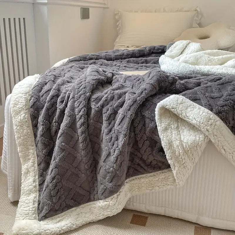 Mjuk och fluffig grå sherpa-filt utbredd på bäddad säng