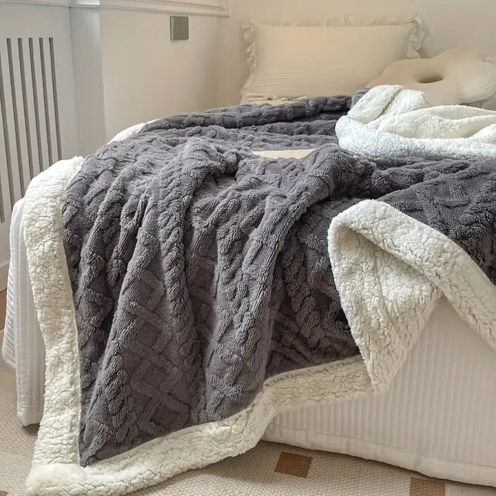 Mjuk och fluffig grå sherpa-filt utbredd på bäddad säng