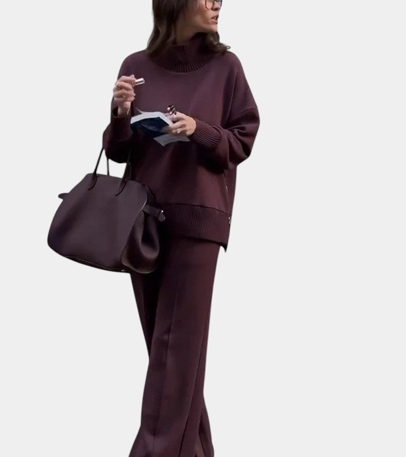 Stående kvinna i elegant vinrött set med polokrage och vida byxor