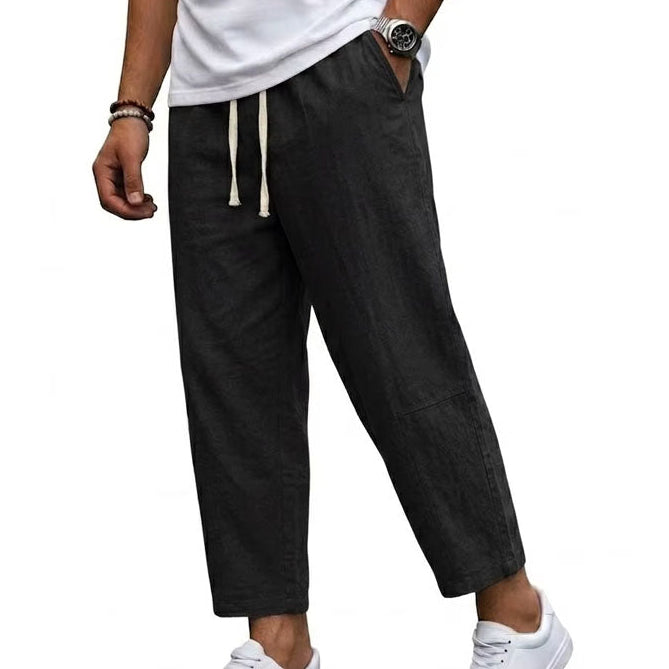 Herr i svarta wide-leg byxor med dragsko och vita sneakers