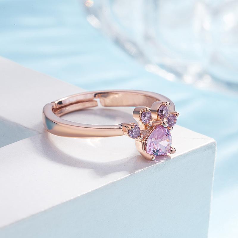 "Justerbar kattfotavtrycksring med zirkon, roséguld och vitt, elegant smycke för kattälskare."