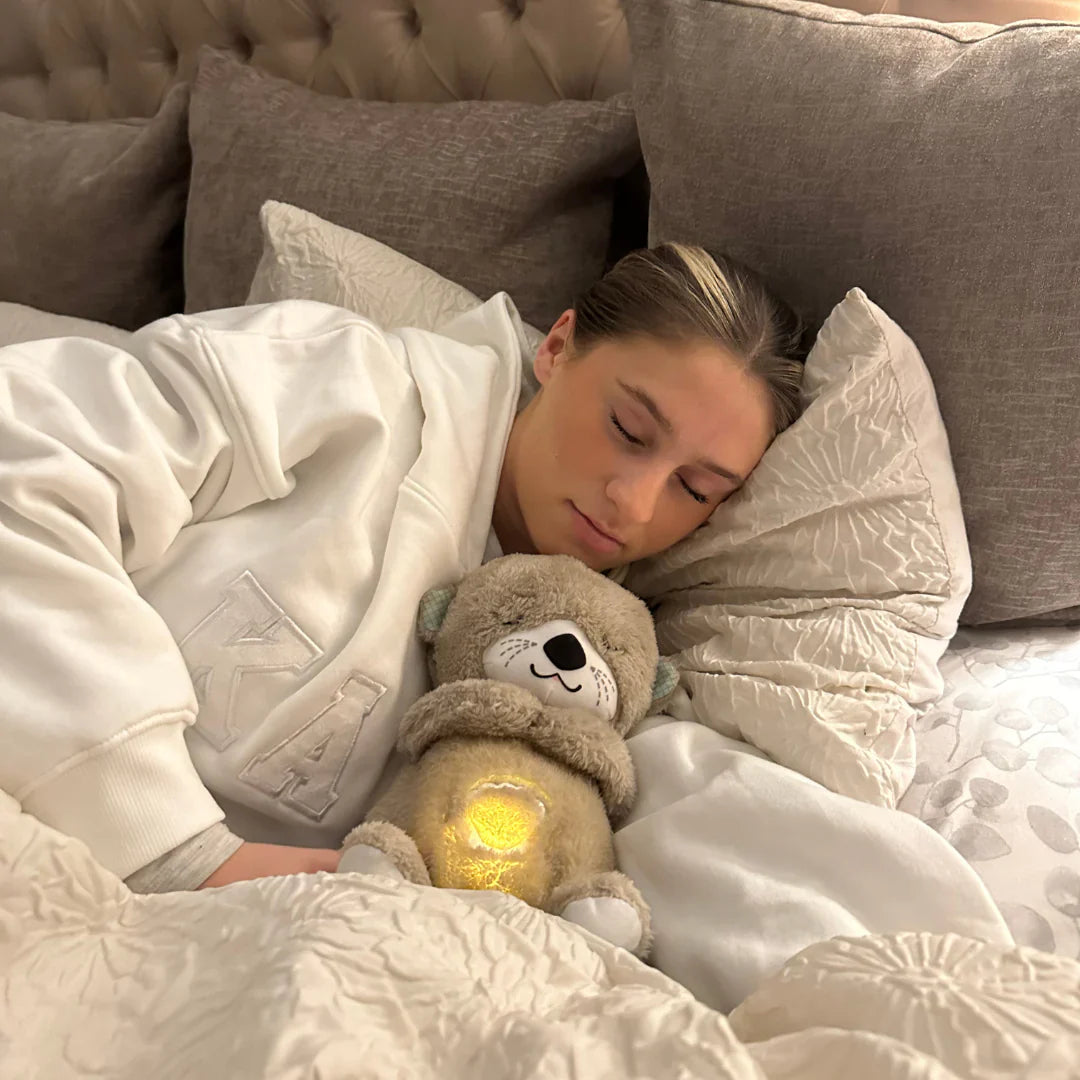Person som sover gott bredvid en SerenitOtter nalle med varmt sken i sängen