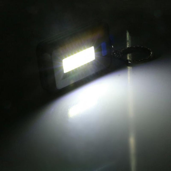 "Kompakt mini LED-ficklampa nyckelring i svart med 3 ljuslägen, perfekt för nattvandring och camping."