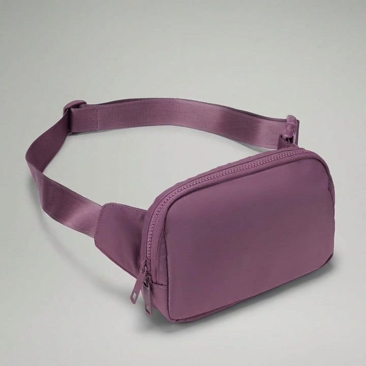 Justerbar rem och hållbart spänne på den kompakta, lätta unisex midjeväskan i svart nylon.