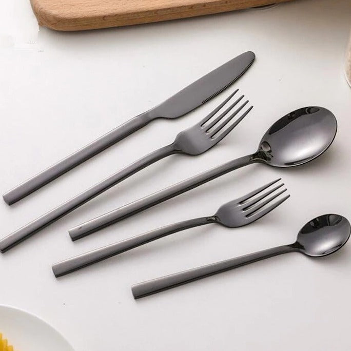 Snygga svarta moderna bestick arrangerade stilrent på bord med servett