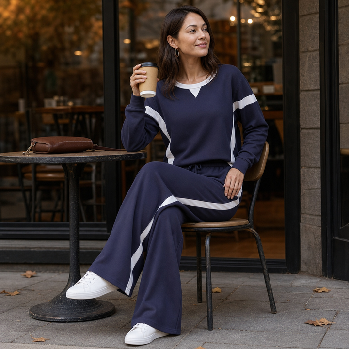 Kvinna som sitter på ett kafé iklädd ett snyggt marinblått damset med sidoband