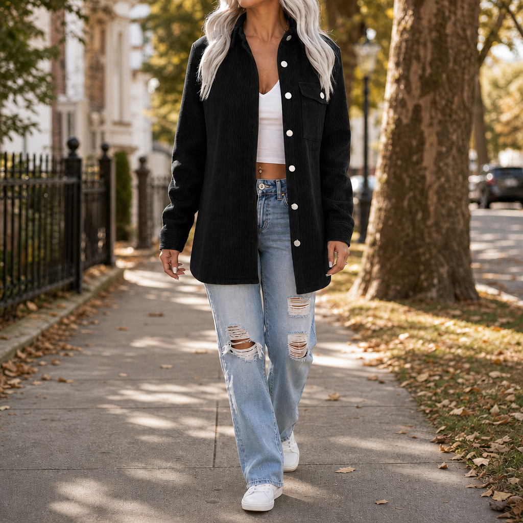 Kvinna som går på gata i svart oversized skjortjacka och vita sneakers