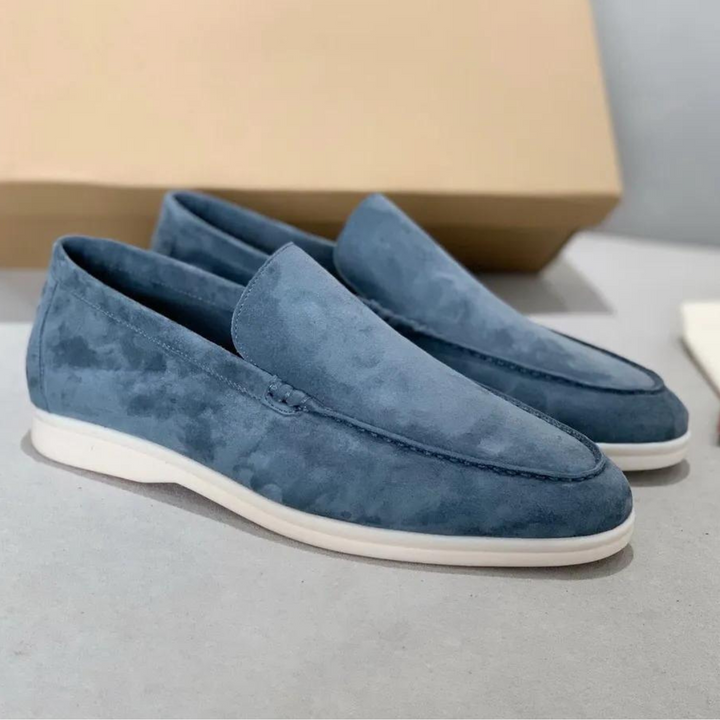 Stilrena blå loafers i mjuk mocka placerade på bord