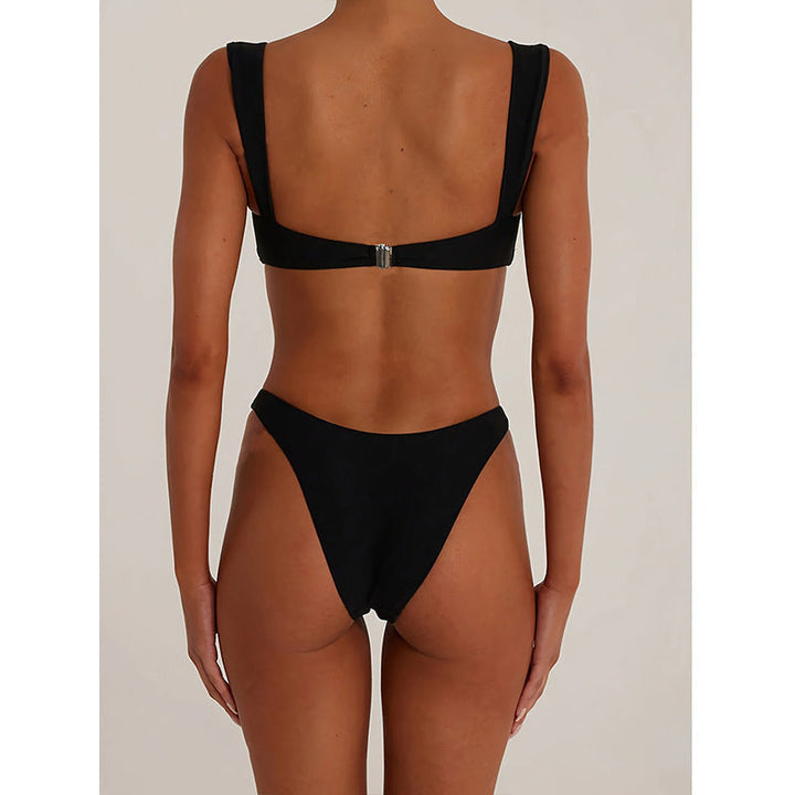 Närbild av gulddetaljerna på den chica svarta bikinin, framhäver den lyxiga designen för strandmode.